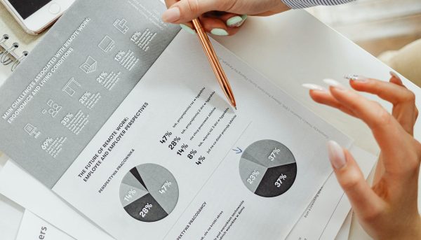 Close-up of businesswoman analyzing financial reports using pie charts in an office setting.