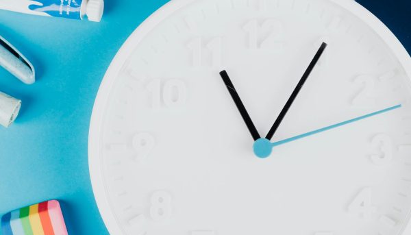 Flat lay of school supplies and a clock on a vibrant blue background.