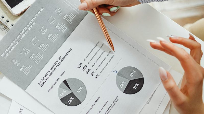 Close-up of businesswoman analyzing financial reports using pie charts in an office setting.